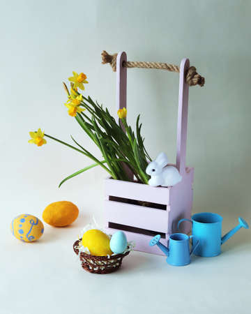 Easter decorations, eggs and a bouquet of spring yellow flowers on a light background, home interior...