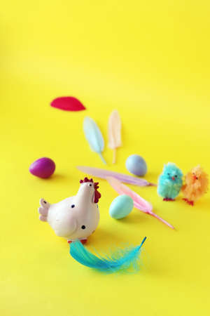 Easter toy chicken, eggs and feathers on bright yellow background, congratulations concept, postcardの写真素材