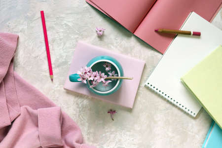 Cup with water and fresh hyacinth flowers, books, notepads, woolen pink sweater on a light background, at home, romantic congratulation, emotion of loveの写真素材
