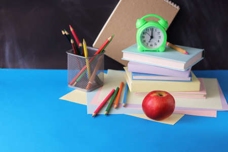 Back to school, books, magnifying glass, apple, notepads and pencils on chalkboard background,...