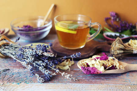 Herbal tea with lemon, dry petals of useful flowers on a wooden tableの写真素材