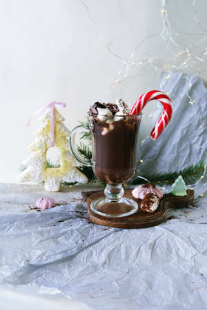 Christmas drink, hot chocolate, meringue, cocoa in a glass cup on a wooden table, toy tree, festive...