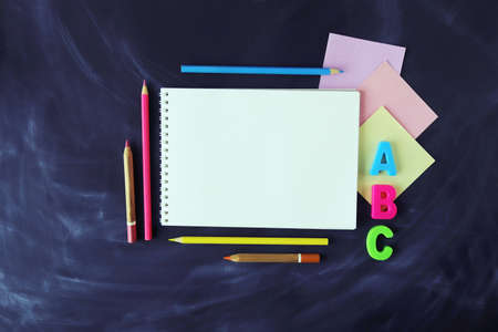 Pencils, paper and sketchbook on chalkboard background, top view, copy space, back to schoolの写真素材