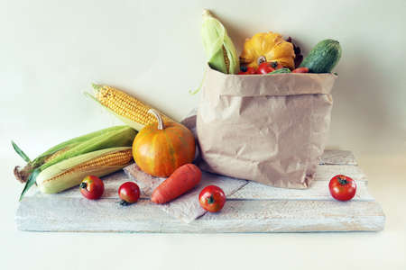Fresh ripe variety of vegetables in an ecological paper bag, on a light background, organic natural...