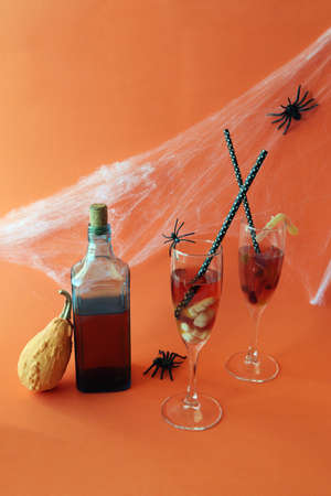 Halloween drinks, wine, pumpkin, spiders and mystical decoration on bright orange backgroundの写真素材