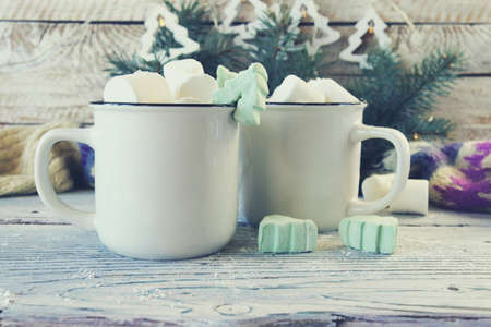 Cups of coffee with meringues and marshmallows, spruce branches, illumination on a wooden background, the concept of celebrating Christmas, New Year, home comfort, congratulationsの写真素材