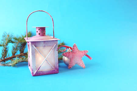 Christmas, lantern with a burning candle, fir-tree branches and balls on a bright background, the...