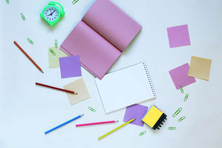 Alarm clock, open books and notepads, school supplies and pastel color note paper on the table, top view, flatly, learning, education, back to school conceptの写真素材