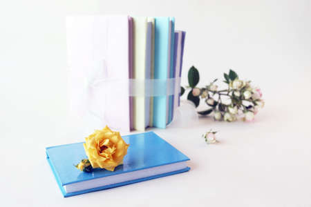 A stack of books with flower bookmarks, fresh roses, yellow, pink and pastel colors, on a light...