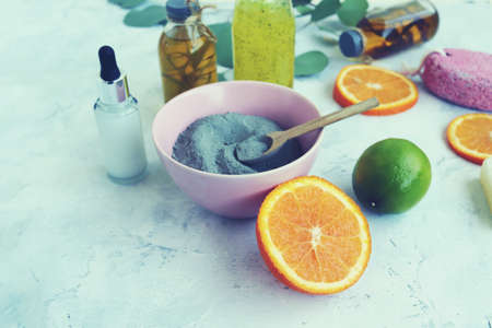 Blue clay, citruses, cream, herbal tinctures and aromatic oils in bottles, eucalyptus leaves on a light background, spa, natural ingredientsの写真素材