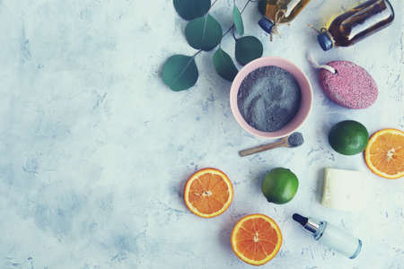 Blue clay, citruses, cream, herbal tinctures and aromatic oils in bottles, eucalyptus leaves on a light background, spa, natural ingredients, top view, flatlyの写真素材
