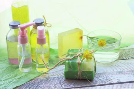 Natural soap, disinfectant spray, oils, tinctures and flowers of celandine on a wooden windowsill,...