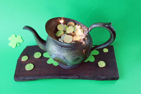 Patrick's Day, vintage pot with gold coins and burning sparklers, on a green background with...