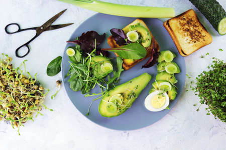 Salad of avocado, boiled eggs, leek, micro greens sprouts and arugula, on a plate on a light table, top view, flatly, natural ingredients, healthy foodの写真素材