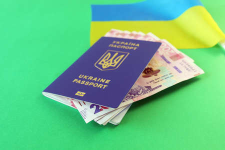 Flag of Ukraine, passport and banknotes of the national currency, on a green background, top view,...