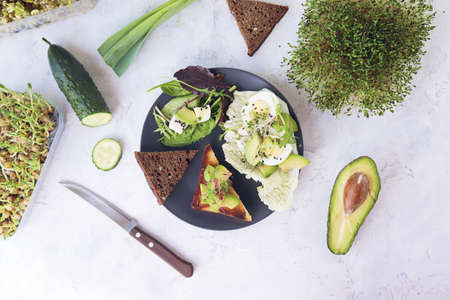 Salad of avocado, boiled eggs, leek, micro greens sprouts and arugula, on a plate on a light table, top view, flatly, natural ingredients, healthy foodの写真素材