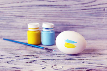 White chicken eggs, yellow and blue paints and brushes on the table concept, symbol, Ukraine, Easter, spring, congratulations, postcardの写真素材