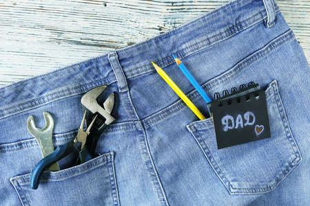 Dad tools in jeans pocket on a wooden background, top view, concept of congratulations on Father's...