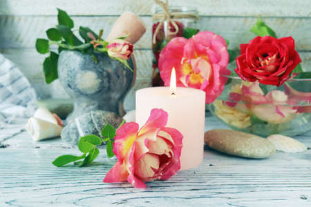 Fresh rose flowers and petal tincture, sea shells and stones, burning candles, on a wooden table, spa concept, natural cosmetics, body care, love emotionの写真素材