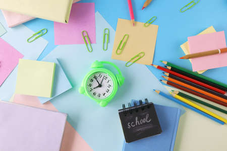 Alarm clock, books and stationery on pastel colors background of colorful paper, back to school, education, student study table, blur focus, copy space, top viewの写真素材