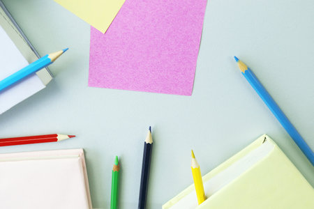 Colorful pencils and notepads on blue background with copy spaceの写真素材