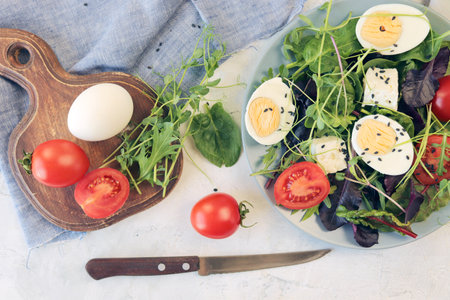 Fresh salad with cherry tomatoes, mozzarella cheese and arugula on a light background.の写真素材