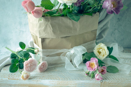 beautiful bouquet of pink roses in a paper bag on a wooden backgroundの写真素材