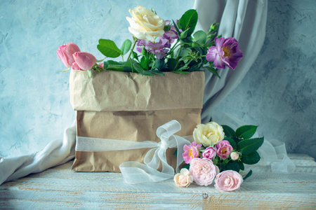Beautiful bouquet of flowers in a paper bag on a wooden backgroundの写真素材