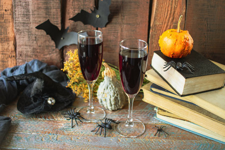 Two glasses of red wine, books, pumpkins and bats on wooden backgroundの写真素材