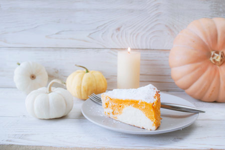 Pumpkin cake on a white wooden background with a burning candleの写真素材
