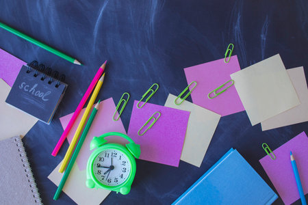 Back to school concept with alarm clock and school supplies on blackboard backgroundの写真素材