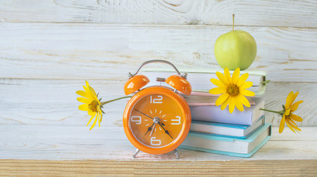 Vintage alarm clock, books and flowers on wooden background with copy spaceの写真素材
