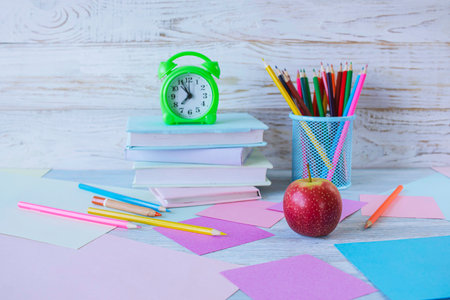 Back to school concept. Stack of books, pencils and apples on wooden background