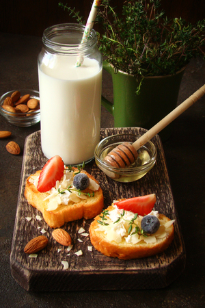 Toast with cream cheese, fresh strawberries, blueberries, almond flakes, blueberries, honeyの写真素材