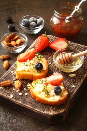Toast with cream cheese, fresh strawberries, blueberries, almond flakes, blueberries, honeyの写真素材