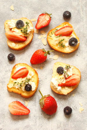 Toast with cream cheese, with fresh berries strawberries, blueberries, almond flakes, thymeの写真素材