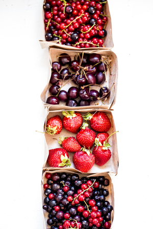 Fresh berry, strawberry, currant, cherry in stock in the paper trays on a white backgroundの写真素材