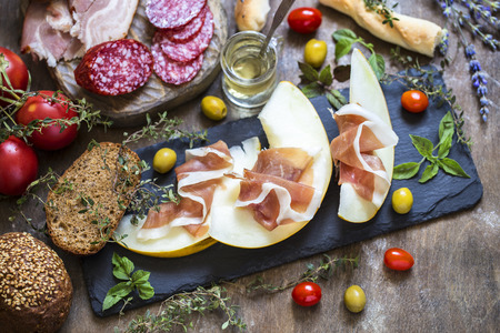 Italian prosciutto with melon, food, olives, sausage, ham and herbs, Basilの写真素材