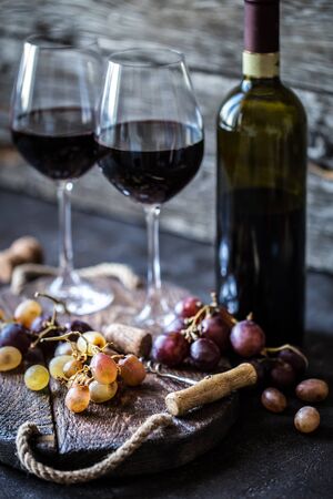Red wine with grapes, meat, glass a glass on a wooden Board in a rustic styleの写真素材