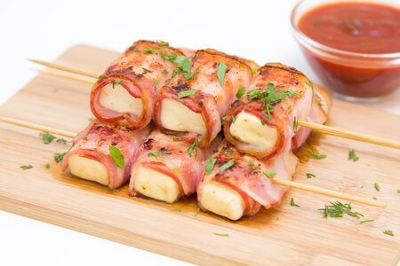 Rolls of feta cheese in bacon with spicy tomato sauce, selective focusの写真素材