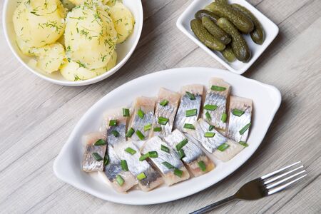 Pieces of herring with onions, gherkins and boiled potatoes. Selective focusの写真素材