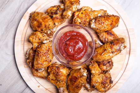 Chicken wings of a barbecue with two sauces on a wooden board. Close-up. Selective focus.の写真素材