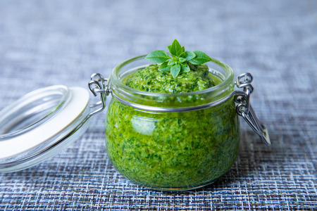 Homemade basil sauce pesto in a glass jar. Close-up, selective focus.の写真素材