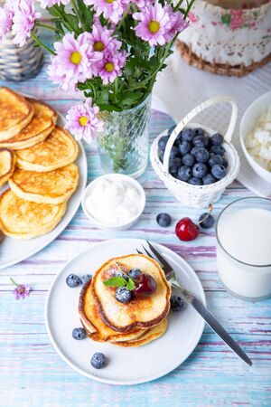Cottage cheese pancakes (syrniki). Homemade cheesecakes from cottage cheese with sour cream, berries and milk. Traditional Russian dish. Close-up.の写真素材
