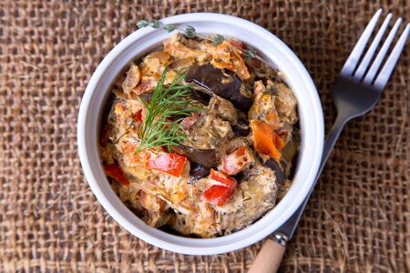Eggplants with tomatoes, bulgarian red (sweet) pepper, onion, dill and sour cream. Vegetarian dish. Close-up.の写真素材