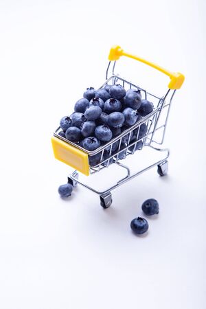 Blueberries in a miniature grocery cart. Close-up, white background.の写真素材