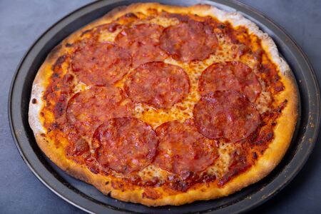 Pizza with chorizo sausage on a black background. Whole pizza. Close-up.の写真素材