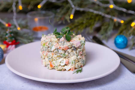 Olivier salad on a white plate, decorated with pea sproutsの写真素材