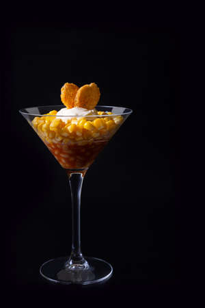Beans, corn and croutons salad in a martini glass. Black background, low key, close-up. Concept.