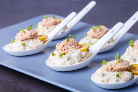 Cold appetizer made from cod liver, cod caviar, olives, cucumber and microgreens on serving spoons....